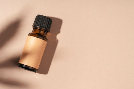 Amber bottle with cannabis oil used for medical purposes on beige background. Daylight and the shadow of a hemp leaf. Soothing cbd oil. Alternative Medicine. Copy spaceの写真素材