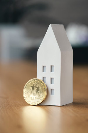 Miniature house with bitcoin gold coin on wooden table. Mortgage concept. Electronic virtual money for online banking. Cryptocurrency investment in real estateの写真素材