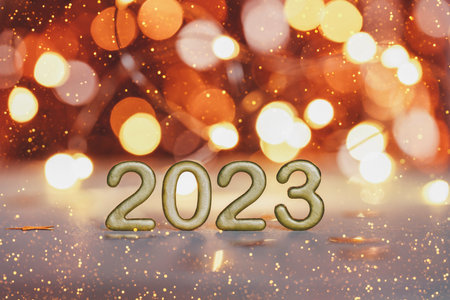 Golden numbers of year 2023. Happy New Year greeting card. Glowing festive garland with bokeh on dark orange background.の写真素材