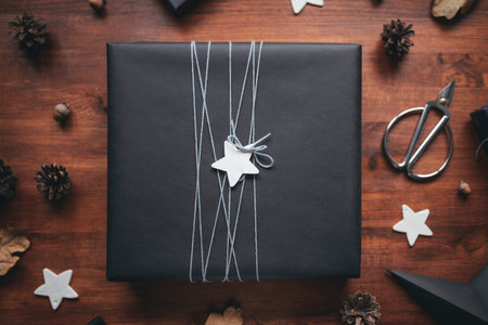 Kraft black gift box with thread in eco packaging with natural decor on a wooden background. Preparation of gifts for the celebration. Christmas, New Year or birthday backdrop. Selective focus on boxの写真素材
