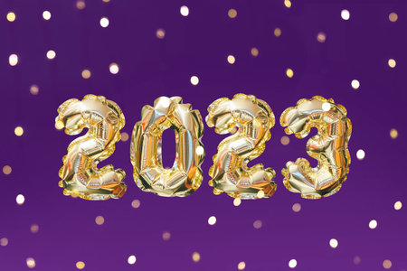 Helium golden balloon number of year 2023. Glowing festive garland with bokeh on purple background. Happy New Year greeting cardの写真素材