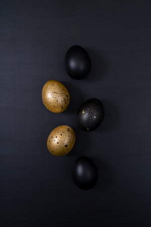 Eggs painted gold and black on dark background. Minimal Easter concept. Golden luxury backdropの写真素材