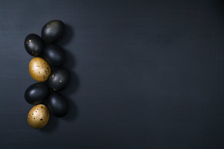 Eggs painted gold and black on dark wooden background. Minimal Easter concept. Luxury backdrop with copy space for text.の写真素材