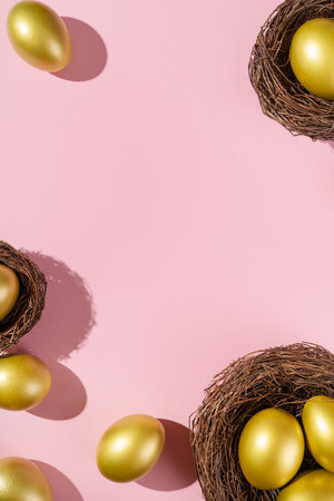 Easter template with golden egg border. Eggs painted gold in nest on pink background. Easter concept with copy space for text. Flat lay style minimalistic design.の写真素材
