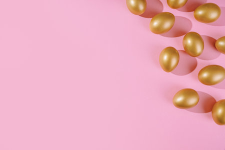 Easter template with golden egg border. Eggs painted gold on pink background. Easter concept with copy space for text. Flat lay style minimalistic design.の写真素材