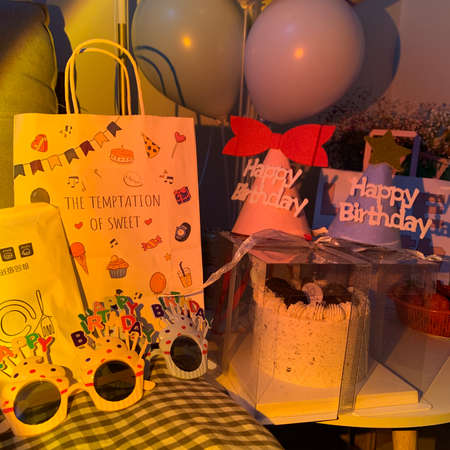 A vertical shot of a birthday cake with balloons and flags in the backgroundの写真素材