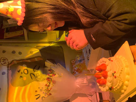 A girl in a green jacket and a black T-shirt decorates a cake with strawberries.の写真素材