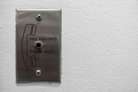 Fire fighterâs phone jack panel mounted on the white wall. It meaning for carefully and be pleasure.の写真素材
