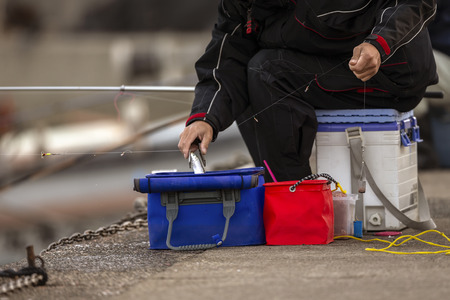 A fisherman catching the fish and keeping it in the bucketの写真素材
