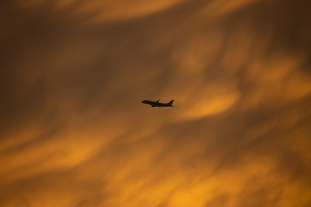 A yellow turbulence cloud with silhouette airplane flyingの写真素材