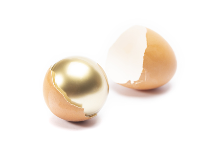 An egg cracked and have golden sphere inside on white background isoratedの写真素材