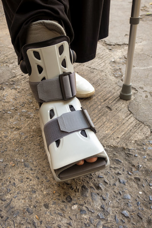 A person with orthopedic shoe and walking stickの写真素材
