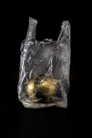 The golden earth in plastic bag concept isolated on black backgroundの写真素材