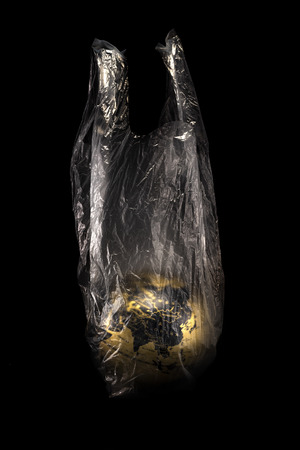 A concept golden earth at Asia (China) inside transparensy plastic bag isolated on black backgroundの写真素材