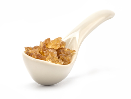 A porcelain spoon with rock sugar inside isolated on white backgroundの写真素材