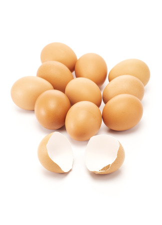 A cracked and open egg in front of other eggs on white background shallow focusの写真素材