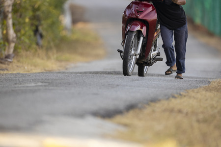 Unlucky man push forward dead motorcycle on the hill shallow focusの写真素材