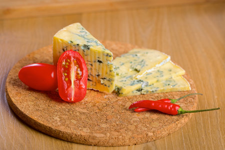 Roquefort blue cheese, tomatos and chilli on a wooden boardの写真素材