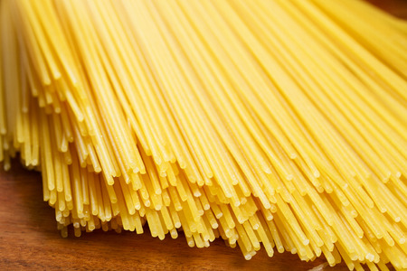 Bunch of italian spaghetti on wooden brown backgroundの写真素材
