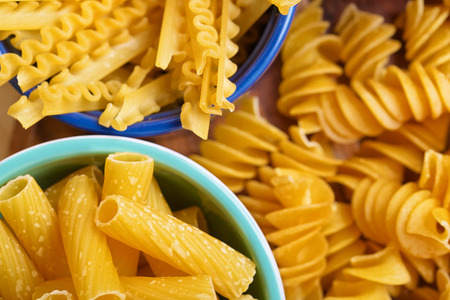 Variety of uncooced italian pasta in cans on wooden boardの写真素材