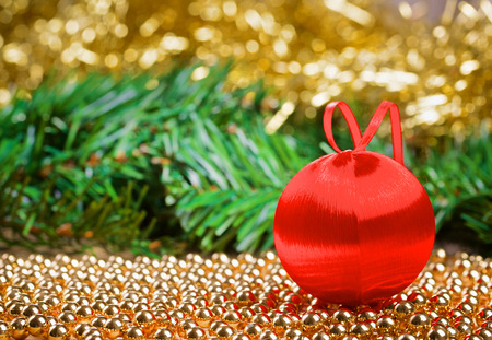 Red christmas ball with yellow tinsel and green fir-tree branchの写真素材