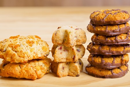 Different cookies in piles on wooden boardの写真素材