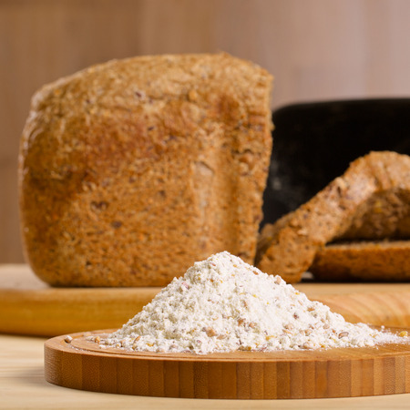 Gluten free flour with cutted fresh bred and breadmaker on wooden table