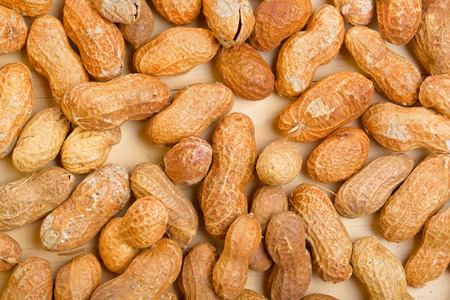 Peanuts in shelles on wooden table as a background