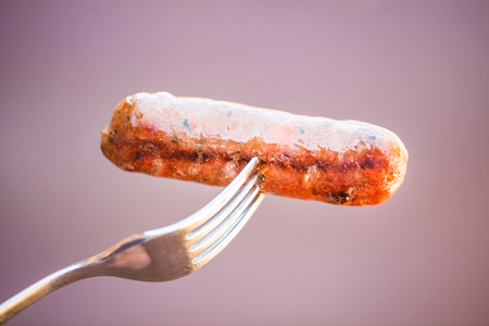 Barbecued beef and pork sausage on forkの写真素材
