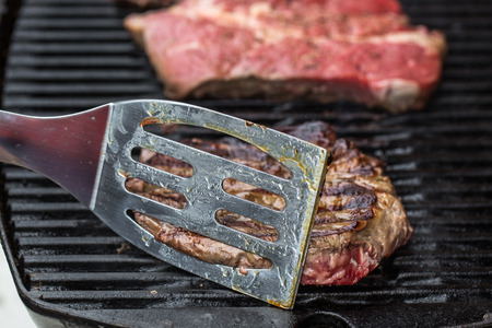 Beef steaks on grill or BBQ with spatulaの写真素材