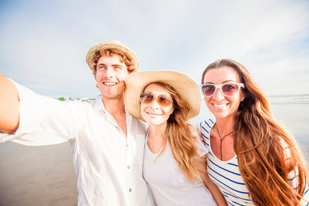 Group of happy young people taking selfie on the beachの写真素材