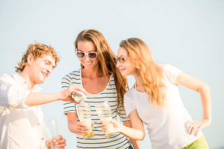 Group of happy young people drinking beer on the beachの写真素材