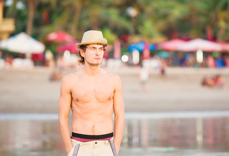 Young fit caucasion guy staying on the beach and thinking of eternityの写真素材