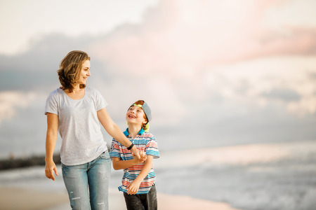 Young happy beautiful mother and her son having fun on the beach on sunset. Positive human emotions, feelings conceptの写真素材