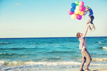 Happy father and son having quality family time on the beach playing with balloons on summer holidays. Lifestyle, vacation, happiness conceptの写真素材