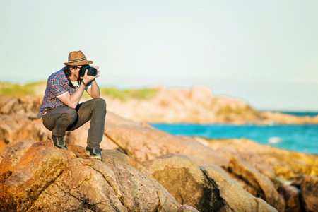 Young photographer taking photos at the beach of the beautiful seascape in sunet light