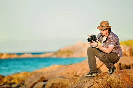 Young photographer taking photos at the beach of the beautiful seascape in sunet light
