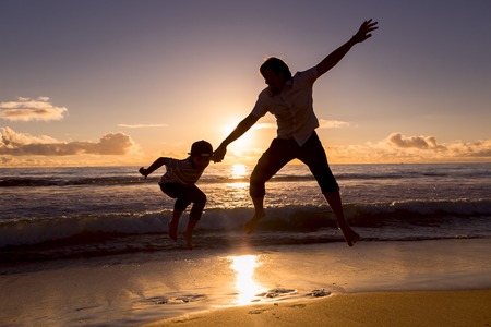 Father and son having fun on the beach on sunset during holidaysの写真素材