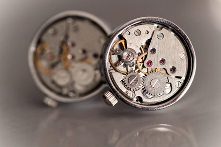 Macro shot of cufflinks with watch mechanism laying on the light surfaceの写真素材