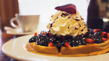 Delicious homemade waffle dessert with strawberries, blueberries, chocolate and whip creamの写真素材