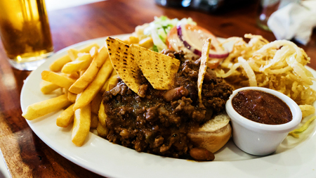 Unhealthy meal with mexican nacho chips loaded with beef, cheese, fries, onion ringsの写真素材