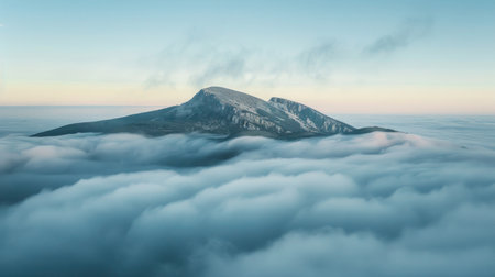 Serene mountain summit surrounded by morning mist and clouds.の素材