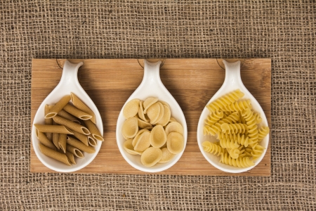Pasta Selection in White Porcelain Bowls on Jute Backgroundの写真素材