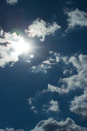 Sun behind the clouds and blue sky in the background