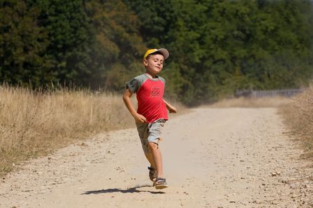 Seven year old kid running on a dusty road in the countrysideの写真素材