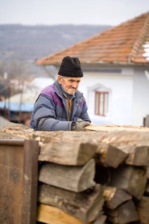 Old peasant man loading logs in a rusty trailerの写真素材