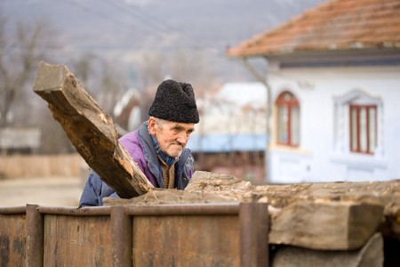 Old peasant man loading logs in a rusty trailerの写真素材