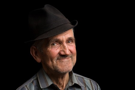 Portrait of a happy old man with hat, isolated on blackの写真素材