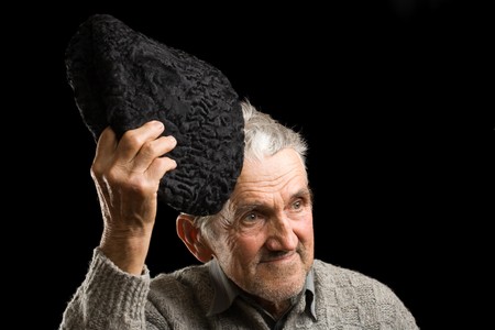 Old man saluting with his cap, isolated on blackの写真素材
