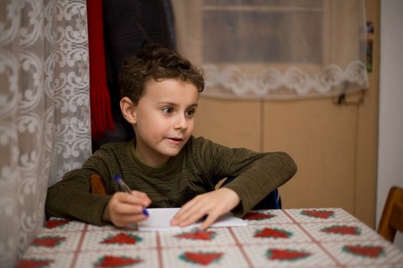 Cute kid writing at a table, very shallow depth of fieldの写真素材